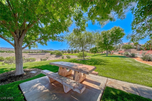 view of home's community with a mountain view, a yard, and a patio area