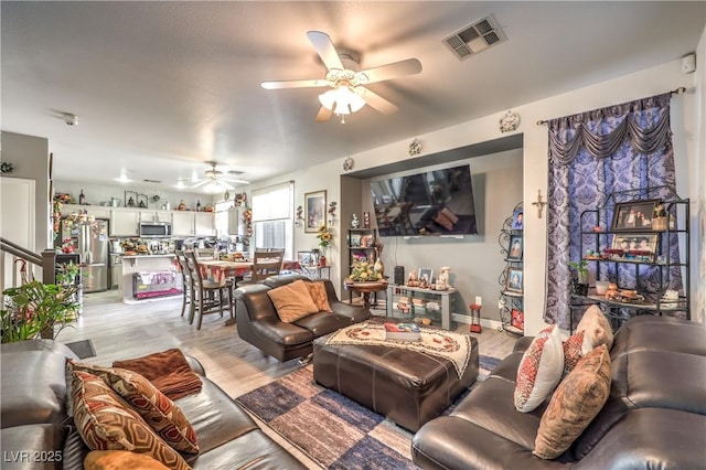 living room with ceiling fan and light hardwood / wood-style flooring