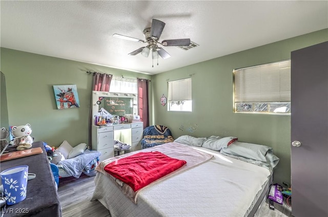 bedroom featuring hardwood / wood-style flooring, a textured ceiling, and ceiling fan