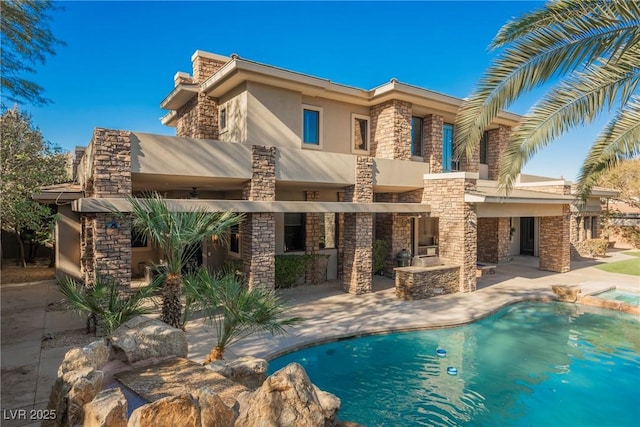 rear view of property with stucco siding, a pool with connected hot tub, stone siding, a patio, and a fireplace