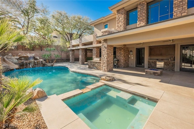 view of swimming pool with a ceiling fan, a pool with connected hot tub, a patio, a water slide, and an outdoor kitchen