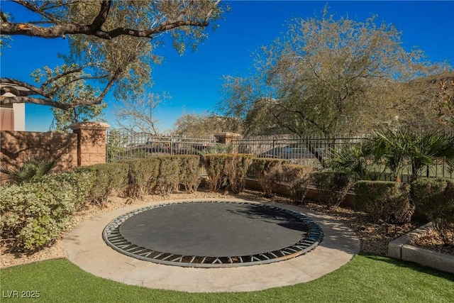 view of yard featuring a trampoline and fence