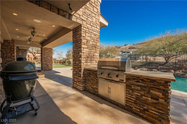 view of patio / terrace with ceiling fan, grilling area, an outdoor kitchen, and fence