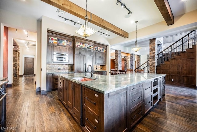 kitchen featuring beam ceiling, glass insert cabinets, dark wood-type flooring, and a sink