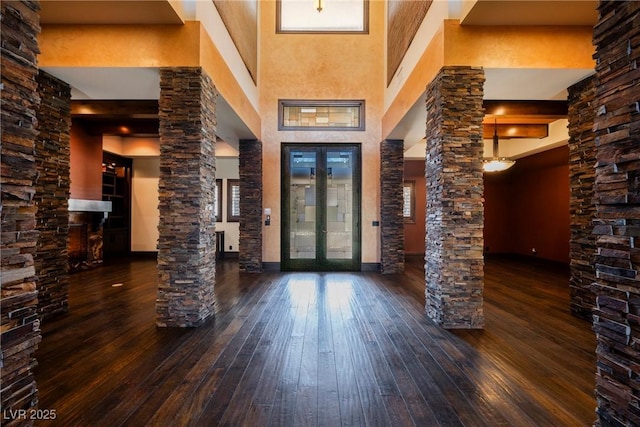 foyer entrance with french doors, a high ceiling, ornate columns, and hardwood / wood-style floors