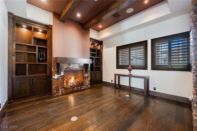 unfurnished living room with hardwood / wood-style floors, baseboards, visible vents, and a premium fireplace