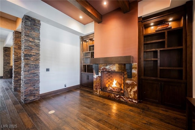 unfurnished living room with hardwood / wood-style flooring, baseboards, a high end fireplace, and beam ceiling