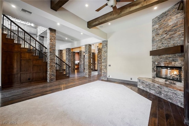 unfurnished living room featuring visible vents, beamed ceiling, stairway, a fireplace, and ornate columns