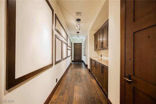 hall featuring dark wood-style floors, visible vents, and baseboards