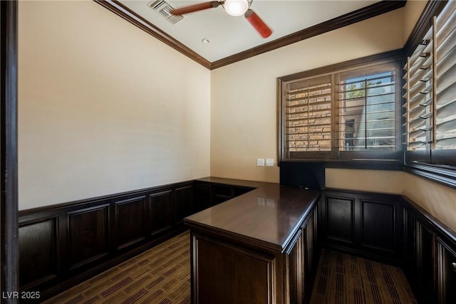 unfurnished office with visible vents, ceiling fan, wainscoting, crown molding, and a decorative wall