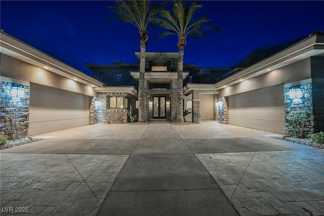 view of front of property featuring stone siding, stucco siding, and driveway