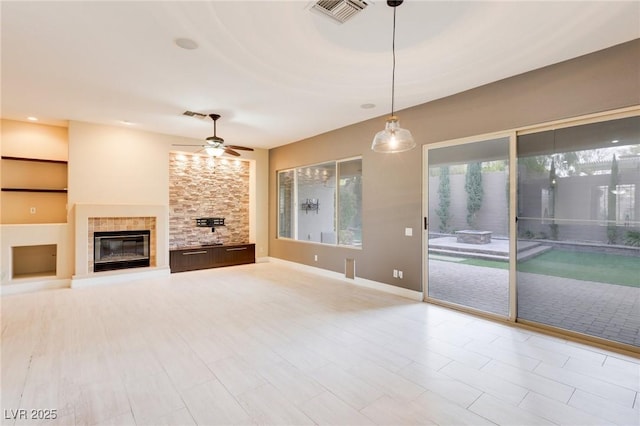 unfurnished living room with a tiled fireplace and ceiling fan