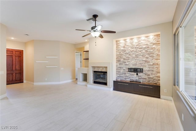 unfurnished living room with a tiled fireplace and ceiling fan