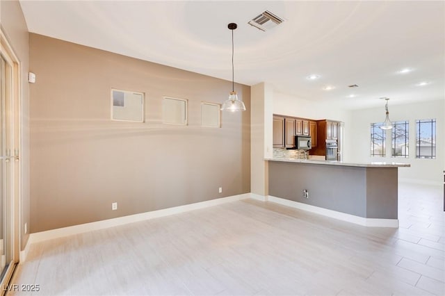 kitchen with oven, a kitchen bar, decorative backsplash, hanging light fixtures, and kitchen peninsula