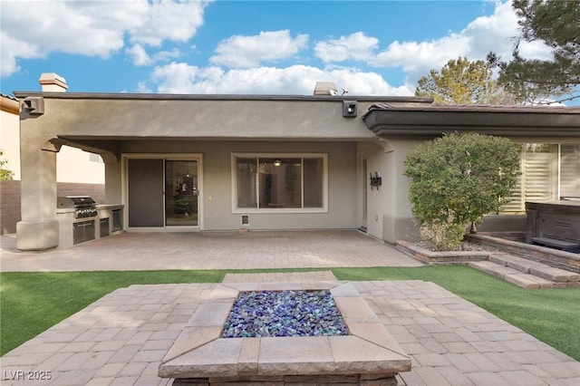 back of property with a patio, an outdoor kitchen, and a fire pit