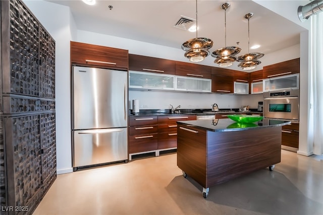 kitchen featuring dark brown cabinetry, appliances with stainless steel finishes, decorative light fixtures, and sink