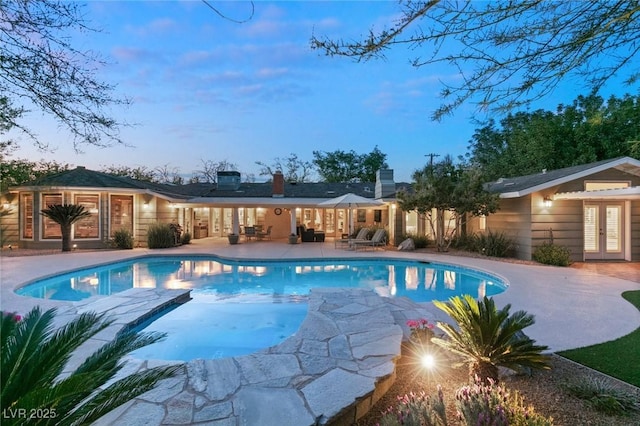 pool at dusk with a patio and french doors