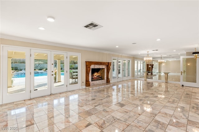 unfurnished living room with french doors, crown molding, and a notable chandelier