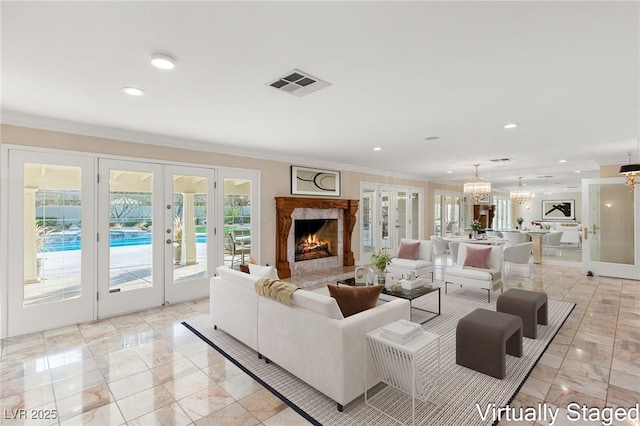 living room with a premium fireplace, crown molding, french doors, and a healthy amount of sunlight