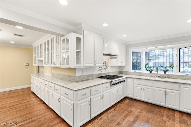 kitchen with premium range hood, white cabinetry, light stone counters, stainless steel gas stovetop, and a healthy amount of sunlight