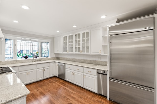 kitchen with white cabinetry, appliances with stainless steel finishes, light stone countertops, and hardwood / wood-style flooring