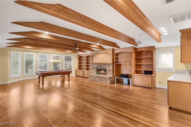 interior space featuring billiards, ceiling fan, beam ceiling, a fireplace, and light hardwood / wood-style floors