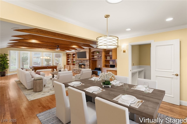 dining area featuring billiards, a stone fireplace, crown molding, light hardwood / wood-style flooring, and beam ceiling