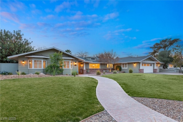 single story home featuring a garage and a lawn