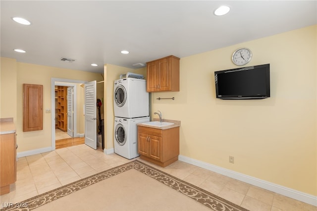 clothes washing area featuring light tile patterned floors, sink, and stacked washer / dryer