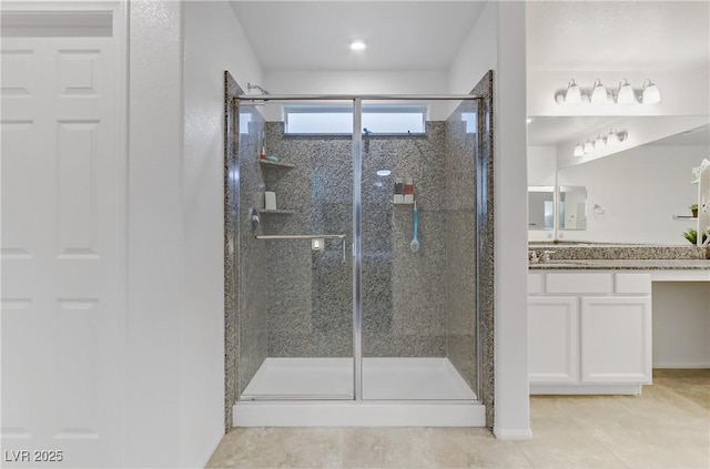 bathroom with a shower with door, vanity, and tile patterned floors