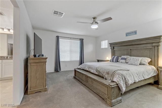 carpeted bedroom featuring ensuite bath and ceiling fan