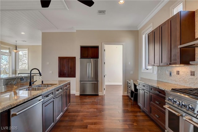 kitchen with pendant lighting, sink, appliances with stainless steel finishes, light stone counters, and ornamental molding