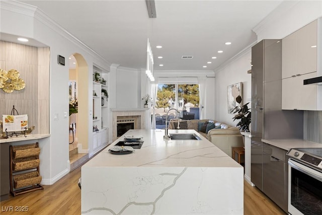 kitchen with modern cabinets, open floor plan, a sink, and stainless steel range with electric cooktop