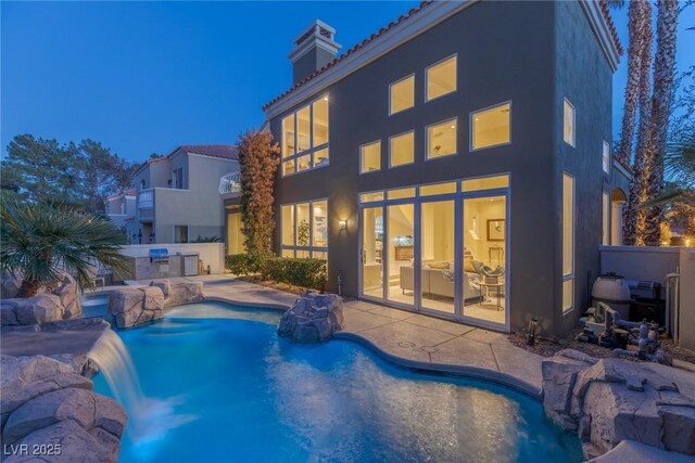 view of swimming pool featuring pool water feature, an outdoor kitchen, and a patio area