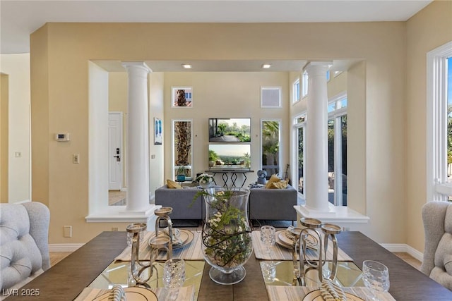 dining space with baseboards, plenty of natural light, and ornate columns