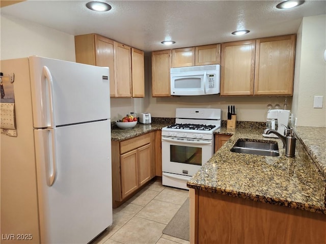 kitchen with sink, light brown cabinets, light tile patterned floors, white appliances, and dark stone counters