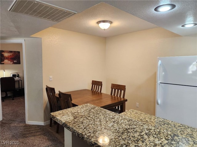 carpeted dining space featuring a textured ceiling