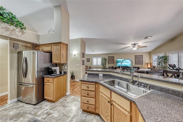 kitchen with a healthy amount of sunlight, vaulted ceiling, sink, and stainless steel fridge