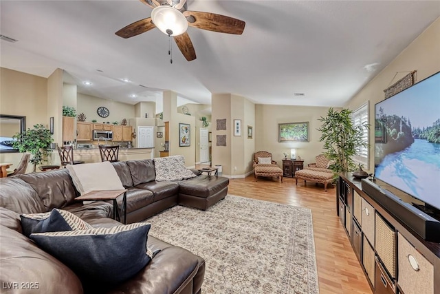 living room featuring ceiling fan, lofted ceiling, and light wood-type flooring