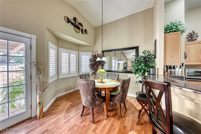 dining space with high vaulted ceiling and light wood-type flooring