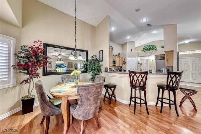 dining space with high vaulted ceiling and light wood-type flooring