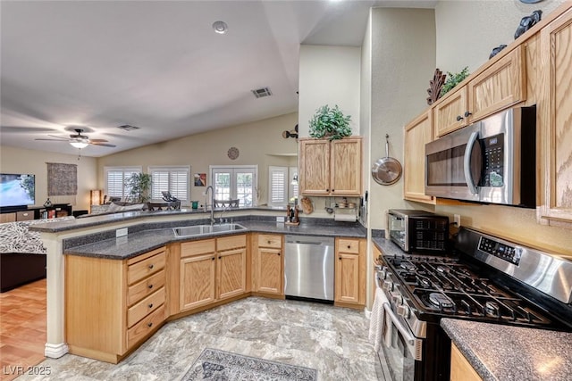 kitchen with sink, appliances with stainless steel finishes, light brown cabinetry, vaulted ceiling, and kitchen peninsula