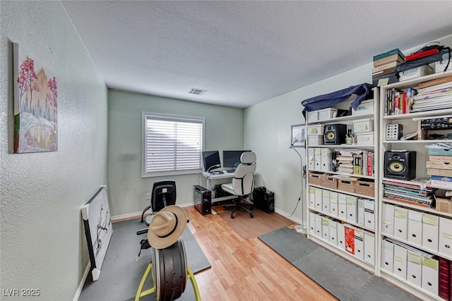 office with light hardwood / wood-style flooring and a textured ceiling