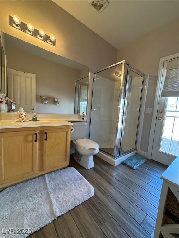 bathroom with an enclosed shower, vanity, wood-type flooring, and toilet