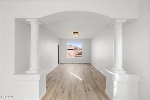 interior space with baseboards, decorative columns, and light wood finished floors