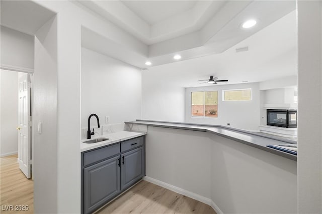 kitchen with baseboards, gray cabinetry, light wood-style floors, a sink, and recessed lighting