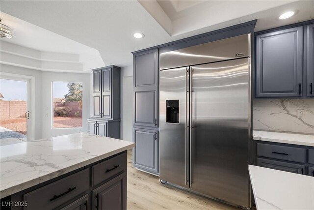 kitchen featuring built in fridge, light wood-type flooring, gray cabinetry, and decorative backsplash