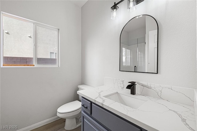 bathroom featuring toilet, wood finished floors, vanity, baseboards, and an enclosed shower