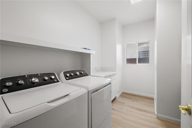 laundry room with washing machine and dryer, baseboards, cabinet space, and light wood finished floors