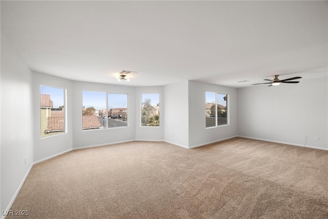 unfurnished room with light carpet, visible vents, baseboards, and ceiling fan